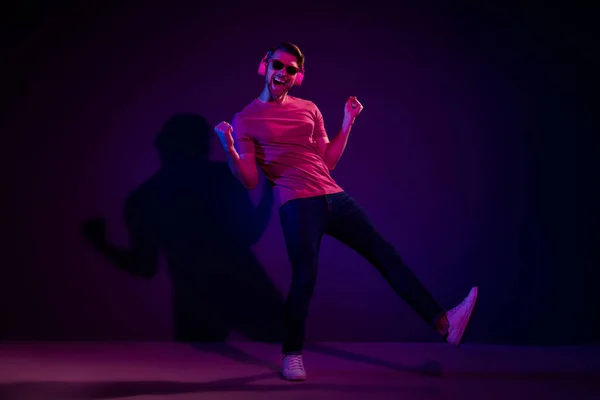 全长体形吸引人的快乐无忧无虑的家伙听着声音跳舞隔离在黑暗的霓虹灯紫色背景上 — 图库照片