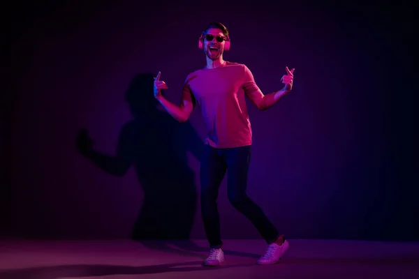Longitud completa cuerpo tamaño vista de atractivo alegre chico escuchar golpe engañar bailando aislado sobre oscuro neón violeta color fondo — Foto de Stock