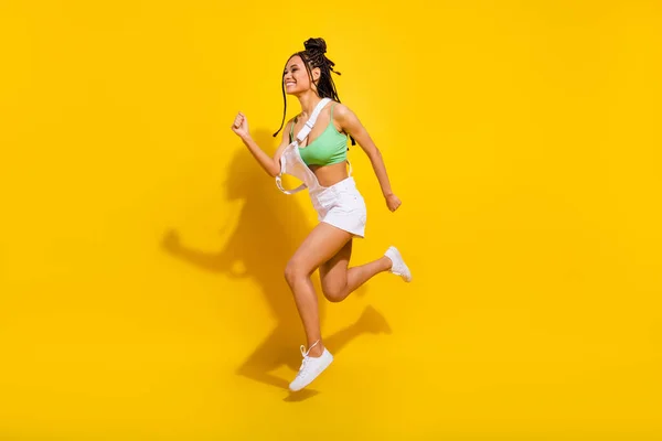 Lunghezza completa foto di bruna afro americana giovane donna saltare fino eseguire spazio vuoto isolato su sfondo di colore giallo — Foto Stock