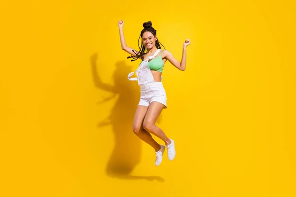 Полноразмерная фотография афроамериканской позитивной молодой женщины, выпрыгивающей победительницей на желтом цветовом фоне — стоковое фото