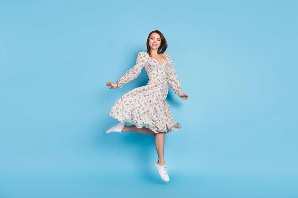Полноразмерная фотография симпатичной коричневой прически барышня прыгает в платье, изолированном на синем фоне — стоковое фото