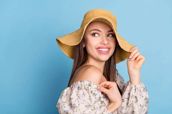 Profil foto av söt brun frisyr ung dam hålla hatt ser tomt utrymme slitage blommig klänning isolerad på blå färg bakgrund — Stockfoto