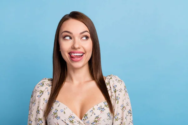 Foto de bonita morena peinado joven mirada espacio vacío lengua fuera usar blusa floral aislado sobre fondo de color azul — Foto de Stock