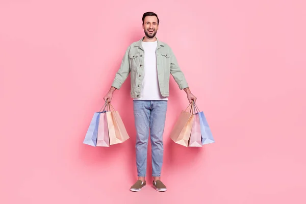 全长体形的迷人而快乐的男人牵着手袋礼物，独立于粉红的彩色背景之外 — 图库照片