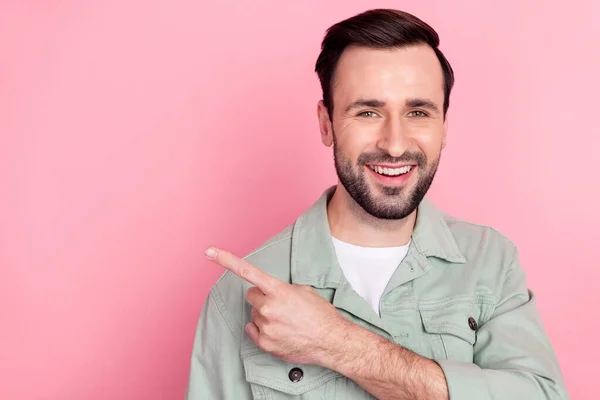 Foto de agradable optimista morena hombre punto espacio vacío desgaste camisa gris aislado sobre fondo de color rosa pastel — Foto de Stock