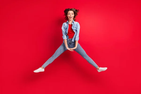 Tamanho do corpo de comprimento total foto de menina alegre descuidada pulando isolado no fundo de cor vermelha brilhante — Fotografia de Stock