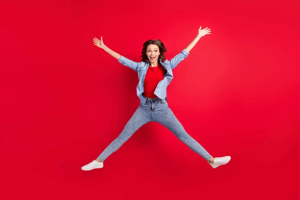 写真の光沢のある愛らしい若い女性の服ジーンズシャツ笑顔ジャンプ高い星のように孤立した赤の色の背景 — ストック写真