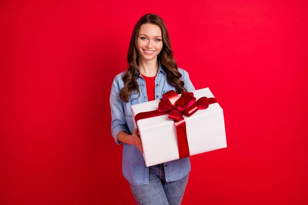 Porträtt av attraktiv glad flicka som håller i händerna festlig presentbox parti isolerad över levande röd färg bakgrund — Stockfoto