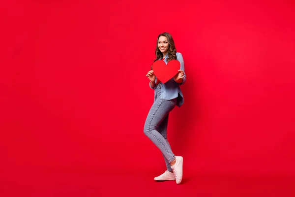 손에 들고 있는 매력적 인 명랑 한 소녀의 전체 몸길이 사진 선명 한 붉은 배경 위에 격리 된 심장 복사 공간 — 스톡 사진