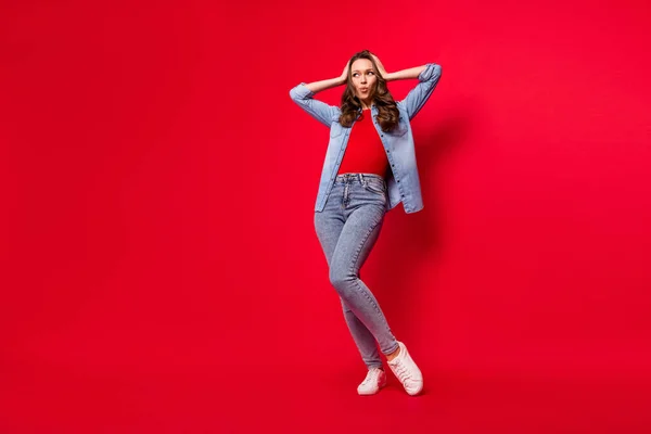Full length μέγεθος του σώματος άποψη ελκυστική κατάπληκτος σύγχυση κορίτσι που θέτουν σκέψης απομονωμένη πάνω από ζωντανό φόντο κόκκινο χρώμα — Φωτογραφία Αρχείου