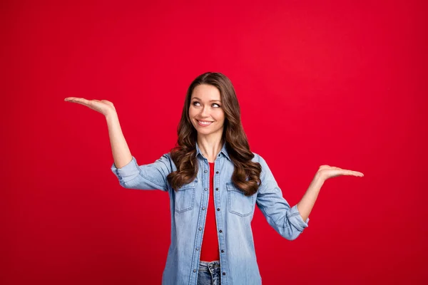 Ritratto di attraente ragazza allegra che tiene su due palme copia spazio annuncio decidere isolato su vibrante sfondo di colore rosso — Foto Stock