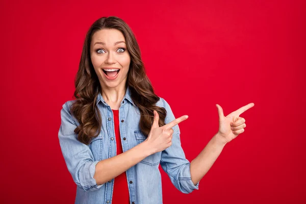 Foto portret van brunette meisje tonen vingers copyspace dolblij verbaasd geïsoleerd op felrode kleur achtergrond — Stockfoto