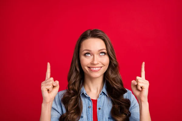 Retrato de atractiva chica de pelo ondulado alegre que aparece la presentación del anuncio aislado sobre el vibrante fondo de color rojo —  Fotos de Stock