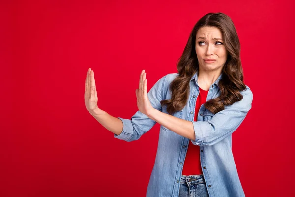 Photo de jeune dame négative ennuyée habillée tenue en denim bras levants aucun espace vide isolé fond de couleur rouge — Photo