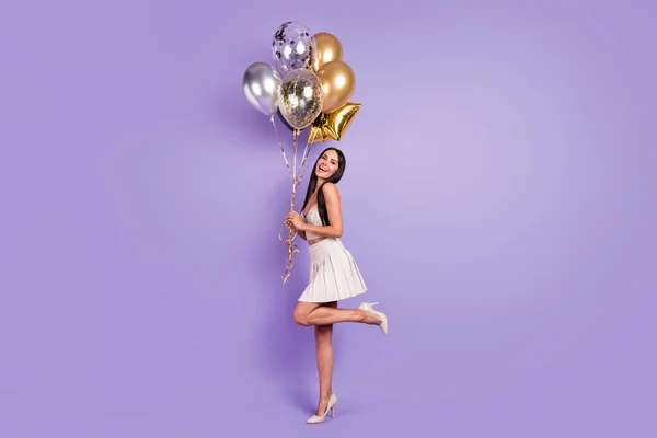 Full size profil stronie zdjęcie uroczej szczęśliwej kobiety trzymać złoty balony uśmiech odizolowany na fioletowy kolor tła — Zdjęcie stockowe
