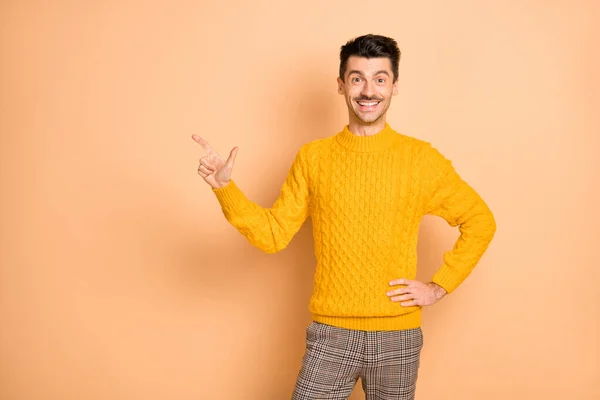 Resimdeki neşeli adam, pastel bej renkli arka planda izole edilmiş boş bir yeri işaret ediyor. — Stok fotoğraf