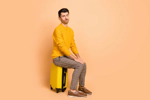 Φωτογραφία πορτρέτο όλο το σώμα άποψη του βαριέται τύπος κάθεται σε βαλίτσα περιμένει απομονωμένο σε παστέλ μπεζ φόντο — Φωτογραφία Αρχείου