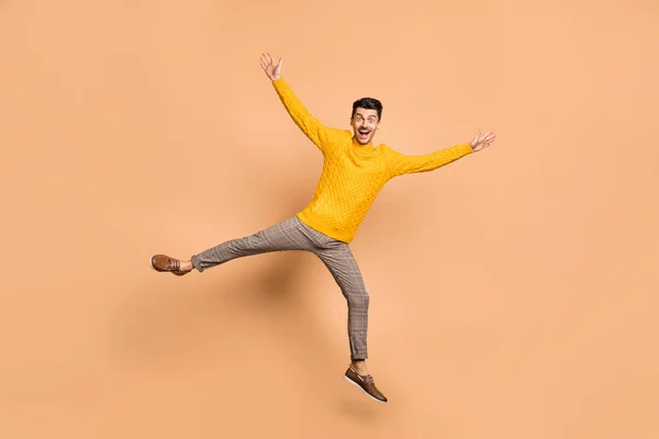 Foto de cuerpo entero retrato de chico excitado extendiendo brazos piernas como estrella saltando aislado sobre fondo de color beige pastel — Foto de Stock