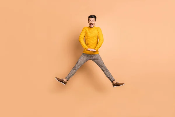 Full längd foto porträtt av upphetsad kille hoppar upp isolerad på pastell beige färgad bakgrund — Stockfoto