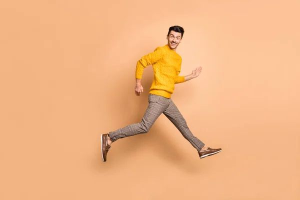 Full längd foto porträtt sida profil man kör hoppa upp isolerad på pastell beige färgad bakgrund — Stockfoto