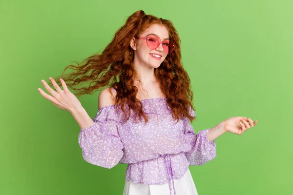 Foto de engraçado gengibre penteado jovem senhora mão cabelo desgaste violeta blusa óculos isolados no fundo de cor verde — Fotografia de Stock