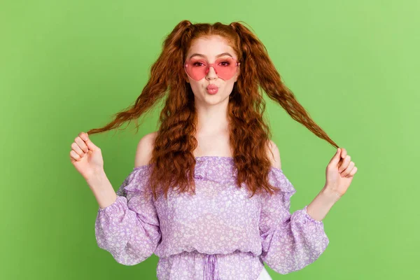 Foto de flerte penteado vermelho milenar senhora mãos cabelo golpe beijo desgaste violeta blusa óculos isolados no fundo cor verde — Fotografia de Stock