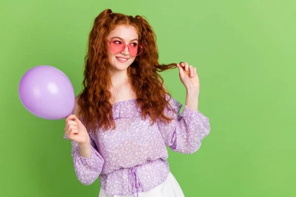 Foto de bonito laranja penteado milenar senhora mão cabelo segurar balão olhar vazio espaço desgaste violeta blusa óculos isolados no fundo cor verde — Fotografia de Stock