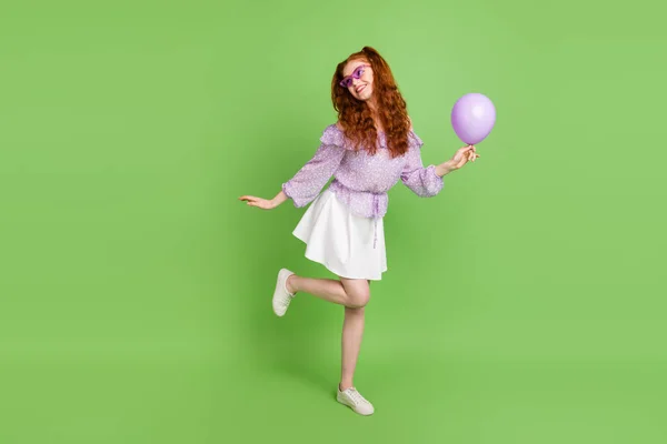 Foto de corpo inteiro de bonito penteado vermelho jovem senhora segurar balão olhar vazio espaço desgaste blusa saia óculos isolados no fundo cor verde — Fotografia de Stock