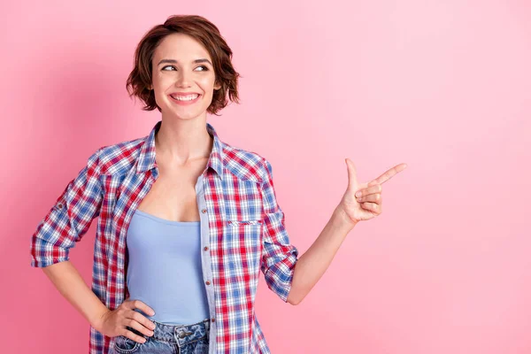 Foto van zoete schattige jonge vrouw dragen geruite shirt wijzend op zoek lege ruimte geïsoleerde roze kleur achtergrond — Stockfoto