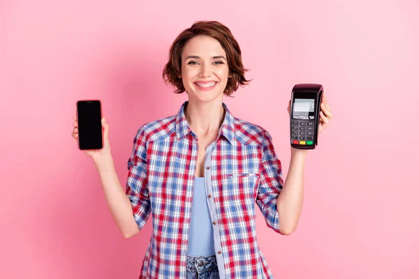 Foto von entzückenden hübsche Frau tragen kariertes Hemd hält Hände Arme Bank Terminal Kreditkarte isoliert rosa Hintergrund — Stockfoto