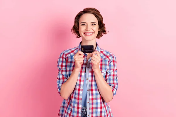 Foto de linda mujer radiante usar camisa a cuadros con las manos brazos tarjeta bancaria aislado color rosa fondo —  Fotos de Stock