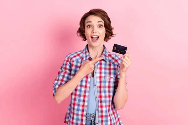 Foto de la mujer afortunada dentada usar camisa a cuadros que sostiene el brazo de la mano de la tarjeta bancaria boca abierta aislado color rosa fondo —  Fotos de Stock