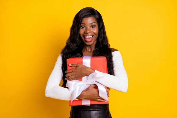 Foto retrato de mulher alegre surpresa mantendo envolto fita presente no birhtday sorrindo isolado fundo de cor amarela vívida — Fotografia de Stock