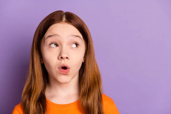 Foto de chica de pelo foxy agradable impresionado mirada espacio vacío desgaste naranja camiseta aislada sobre fondo de color púrpura —  Fotos de Stock