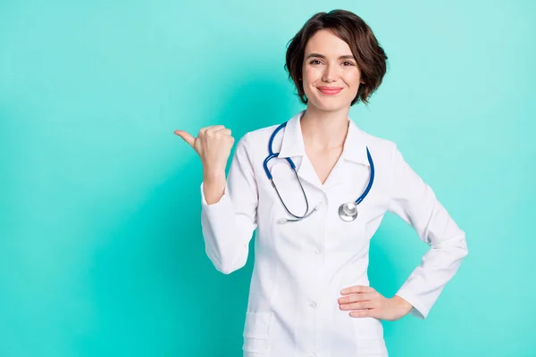 Fénykép fiatal nő orvos boldog mosoly jelzi hüvelykujj üres tér tanácsadás hirdetés választás sugallják elszigetelt felett varangy szín háttér — Stock Fotó