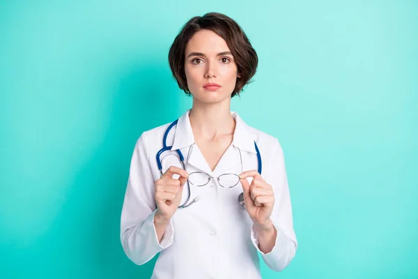 Retrato fotográfico de doctora seria vistiendo uniforme blanco con estetoscopio aislado color verde azulado — Foto de Stock