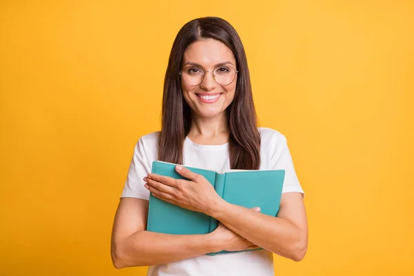 Ritratto di attraente donna intellettuale allegra abbracciando libro di lettura isolato su sfondo giallo brillante — Foto Stock