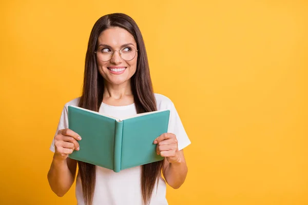 Portrait of attractive cheerful woman reading book looking aside copy empty space isolated over bright yellow color background — Stock Photo, Image