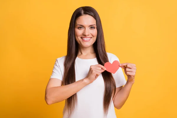 Foto de mulher madura atraente segurar vermelho coração de papel sorriso agradável isolado no fundo de cor amarela brilho — Fotografia de Stock