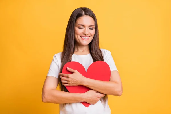 Foto retrato de mulher abraçando vermelho papel coração amor símbolo fechado olhos copyspace isolado em vibrante cor amarela fundo — Fotografia de Stock