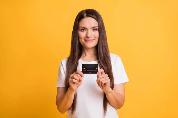Photo portrait of smiling business woman keeping debit bank card wearing white t-shirt isolated on vibrant yellow color background — Stock Photo, Image