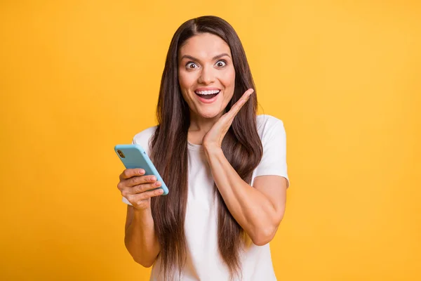 Foto portret van mooie vrouw verbaasd houden mobiele telefoon staren palm in de buurt gezicht verrast geïsoleerd op felgele kleur achtergrond — Stockfoto