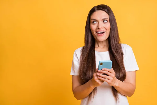 Zdjęcie portret ciekawej kobiety korzystającej z aplikacji na smartfonie social media patrząc copyspace izolowane na żywym żółtym tle — Zdjęcie stockowe