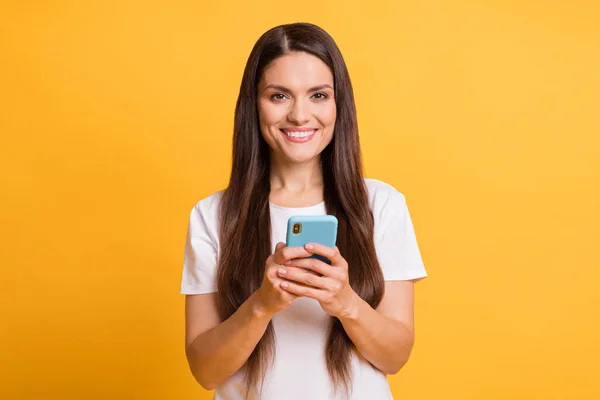Foto porträtt av kvinnliga bloggare surfa internet hålla mobiltelefon ler isolerad på ljusa gula färg bakgrund — Stockfoto