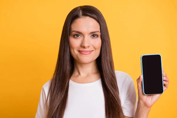 Retrato fotográfico de una hermosa mujer que muestra la pantalla del teléfono móvil con espacio en blanco sonriendo aislado sobre un vibrante fondo de color amarillo — Foto de Stock