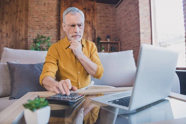 Foto van gedachte vlier wit haar man werk laptop hand gezicht zitten dragen bril geel shirt alleen thuis — Stockfoto