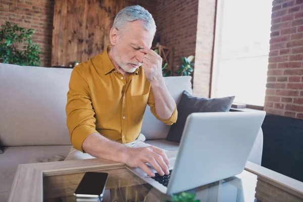 Portrait of unsatisfied aged person sit on sofa closed eyes arm fingers touch nose feeling bad home indoors — Stock Photo, Image