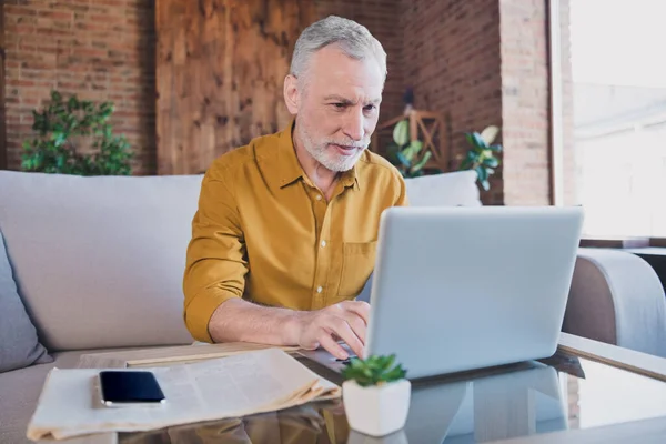 Foto van vrolijke oude man zitten op bank look gebruik laptop schrijven co werken hebben goed humeur thuis binnen — Stockfoto