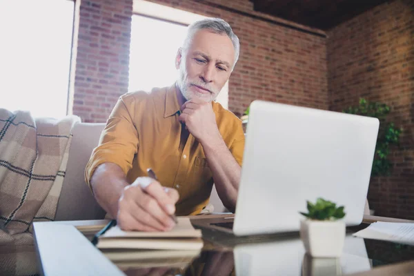 Porträt eines gutaussehenden Mannes sitzt auf Sofa Arm auf Kinn Blick interessiert Notizbuch Notizen Liste zu tun, drinnen — Stockfoto