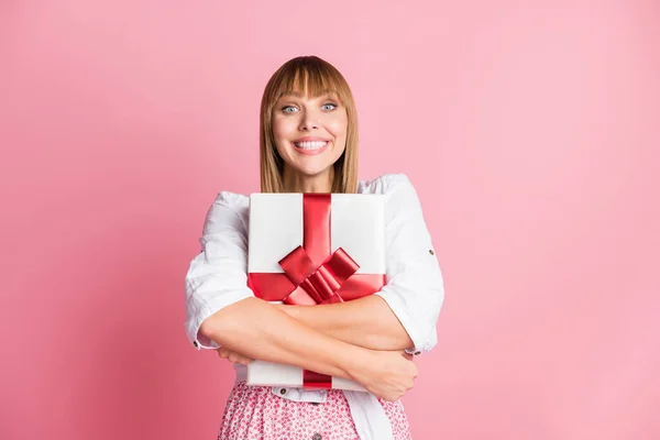 Foto portrét mladá dívka objímající slavnostní narozeniny dárek v krabici s stuhou s úsměvem izolované na pastelové růžové pozadí — Stock fotografie